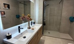 reforma de baño acogedor con muebles de madera y espejo moderno