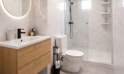 baño moderno con espejo redondo y luminoso