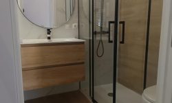 reforma de baño con mueble de madera y mampara negra