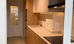 Reforma de cocina con armarios de madera, extractor negro y puerta trasera