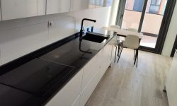 reforma de cocina moderna, encimera larga con ventanal al final