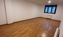 Salón amplio con suelo de parqué, instalación de radiadores, y ventana a medida.